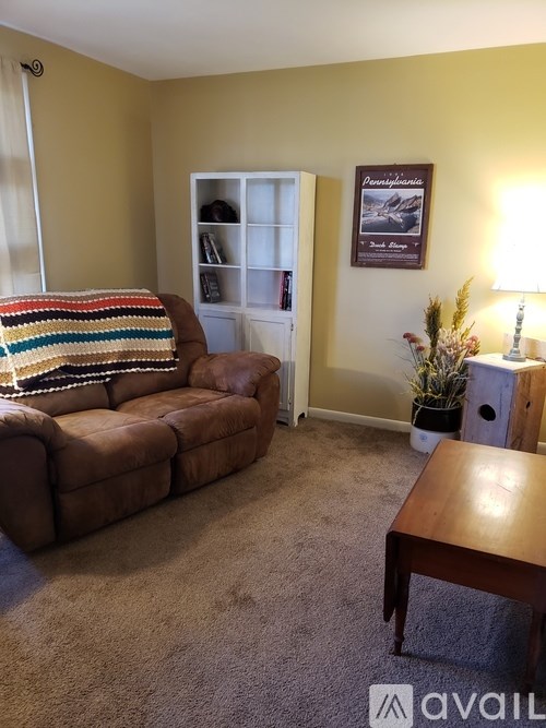 A living room with a brown leather couch and a white bookshelf.