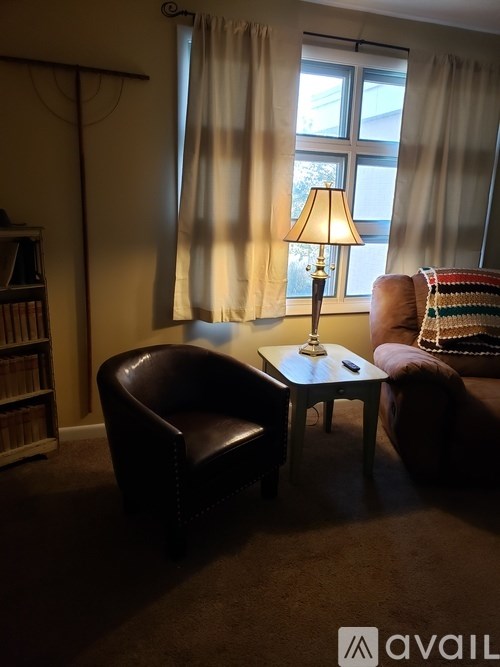 A lamp on a table in a room with a chair and a couch.