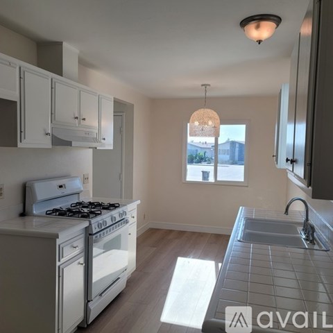A kitchen with a white stove and cabinets.