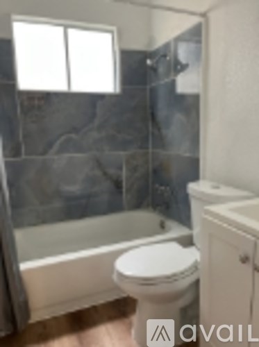 A bathroom with a toilet, tub, and window.