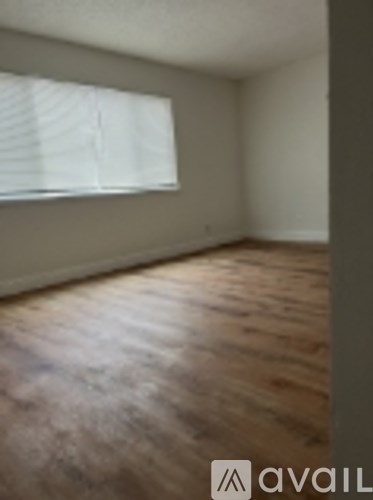 A room with wooden floors and a window with blinds.