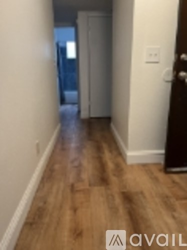 A hallway with a wooden floor and a door at the end.