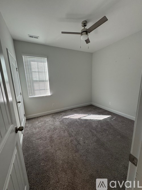 A room with a ceiling fan and carpeted floor.
