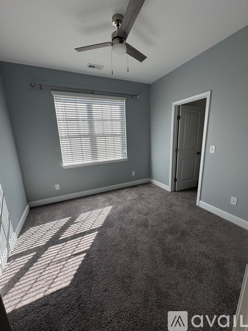 A room with a carpet, a ceiling fan, and a window with blinds.