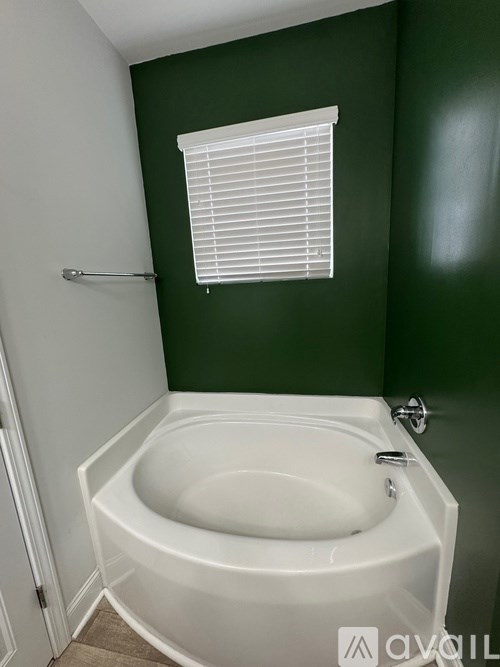 A white bathtub in a bathroom with green walls.