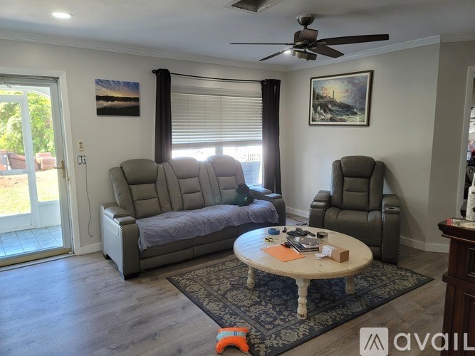 A living room with a grey sofa, a grey armchair, a wooden coffee table, and a ceiling fan.
