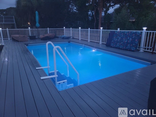 A pool with a wooden deck and a white railing.