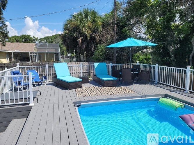 A pool with a deck and chairs is surrounded by a fence.
