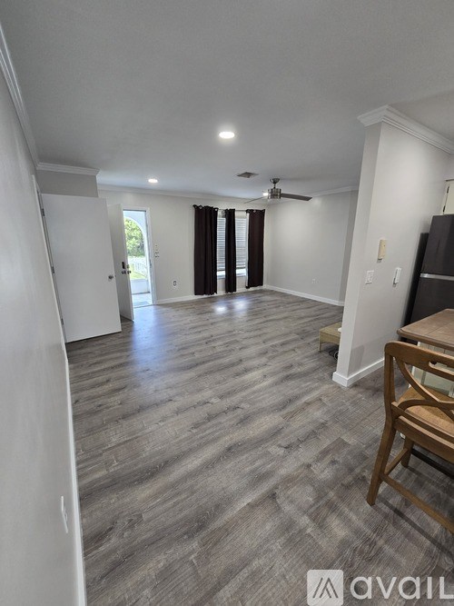 A spacious room with wooden flooring and a ceiling fan.