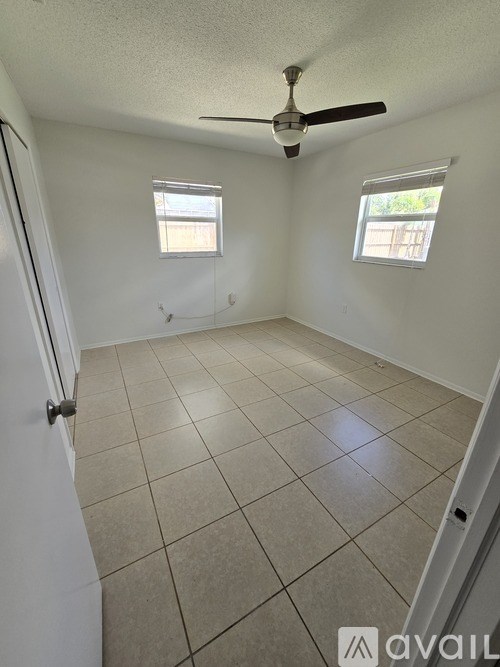 A room with a ceiling fan and two windows.