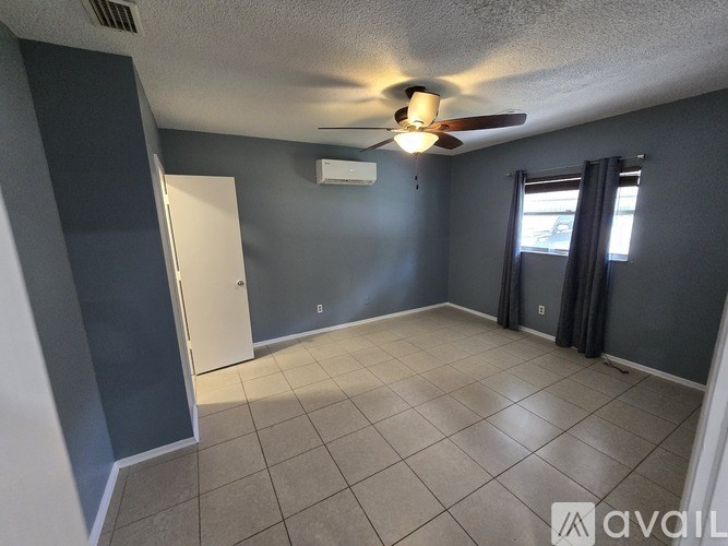 A room with a ceiling fan and a window with curtains.