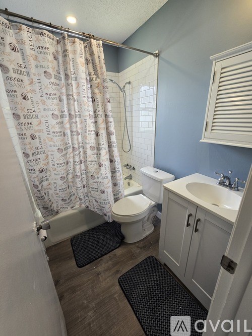 A bathroom with a shower curtain that has words like "ocean" and "wave" on it.