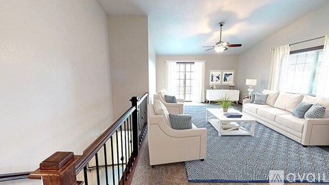 A living room with a white couch and a blue rug.