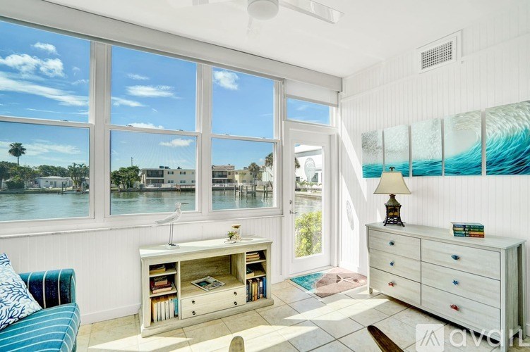 A room with a white couch and a large window overlooking a body of water.