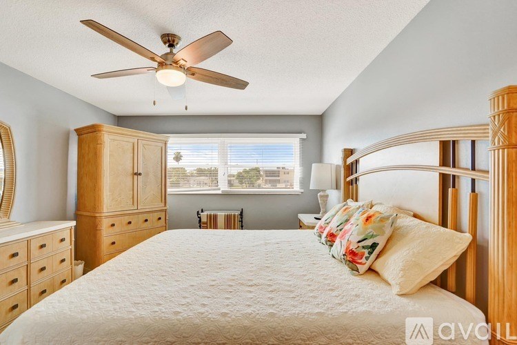 A bedroom with a large bed, wooden furniture, and a ceiling fan.