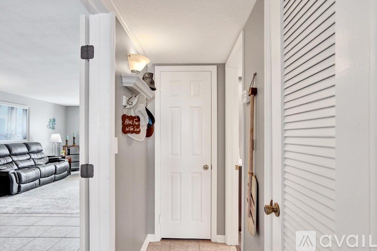 A white door with a gold handle is in a hallway.