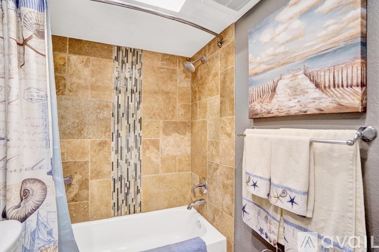 A bathroom with a shower curtain and a painting on the wall.