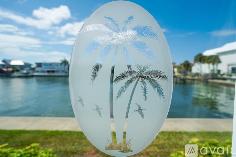 A round glass object with palm trees and birds etched into it.