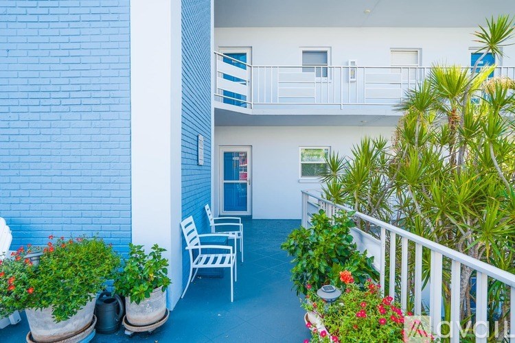 A balcony with a white railing, a chair, and potted plants.