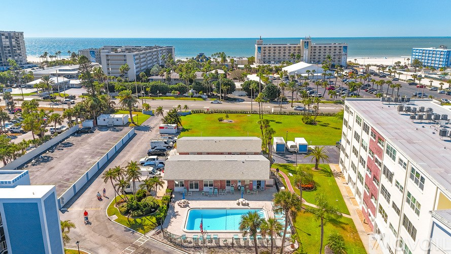 A painting hangs on the wall above a wooden table with a white lamp and a glass vase on it.