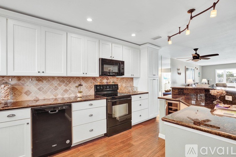 A kitchen with white cabinets and a dark countertop.