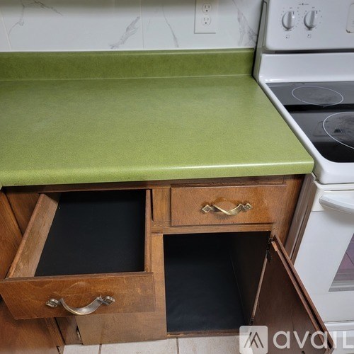 A kitchen with a green countertop and wooden drawers.