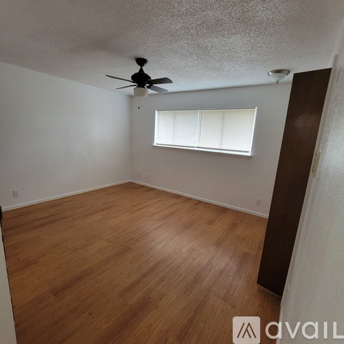 A room with a ceiling fan and wooden flooring.