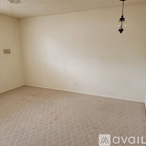 A room with a carpeted floor and a hanging light fixture.