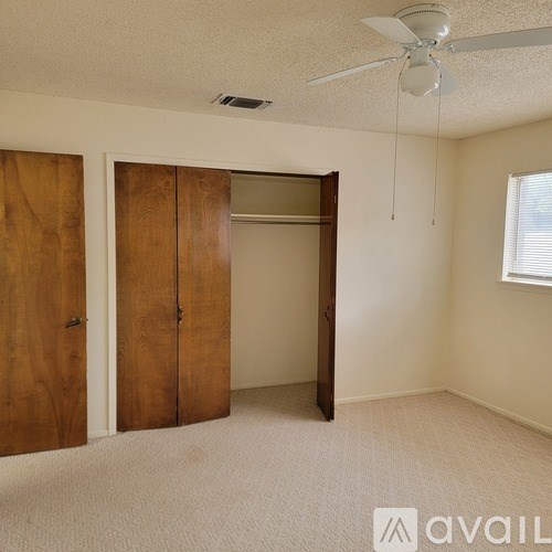 A room with a ceiling fan and a window with blinds.