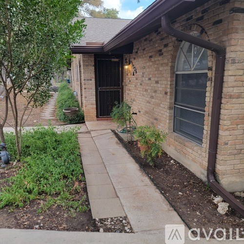 A brick house with a black door and a small garden in front.