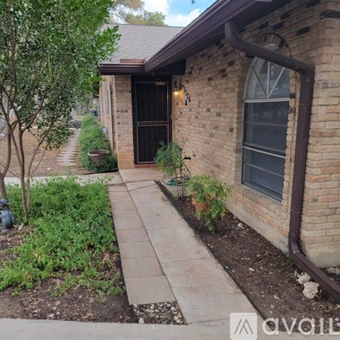 A brick house with a black door and a small garden in front.