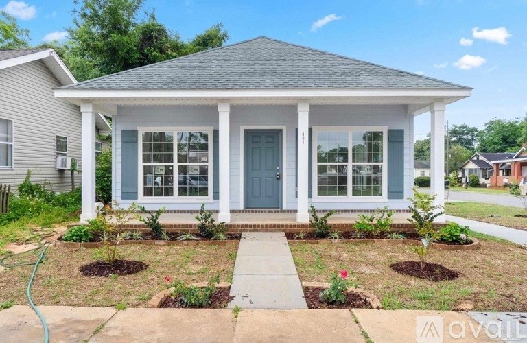 A small house with a front yard and a hose.