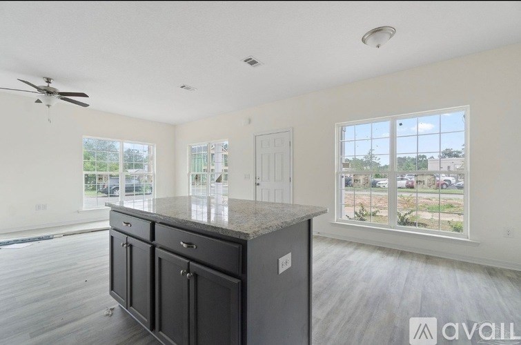 A spacious kitchen with a marble countertop and a ceiling fan.