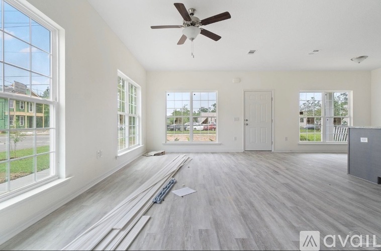 A spacious room with a ceiling fan and large windows.