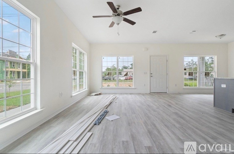A spacious room with a ceiling fan and large windows.
