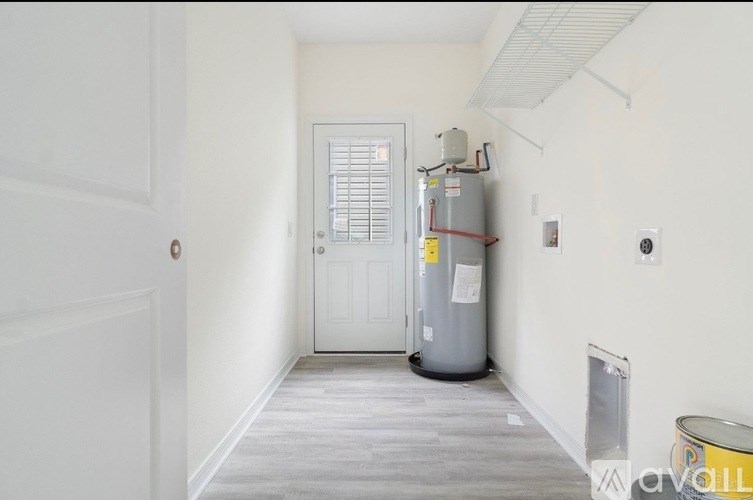A room with a door and a water heater.