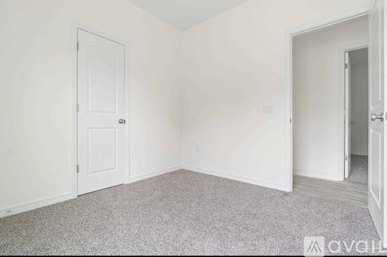 A room with a carpeted floor and two doors.