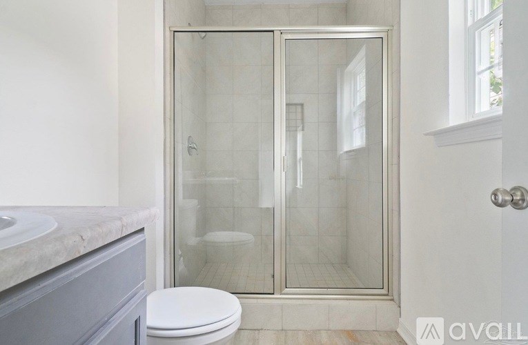 A bathroom with a toilet, sink, and a glass shower stall.