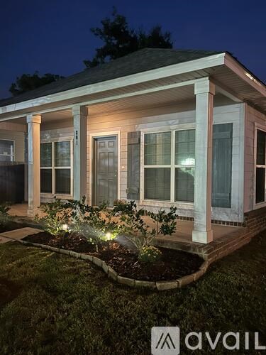 A house with a porch and lights on the plants.