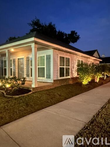 A house with a porch and lights on at night.