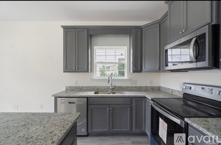 A kitchen with granite countertops and dark cabinets.