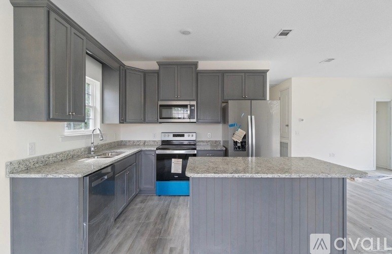 A kitchen with a granite countertop and grey cabinets.