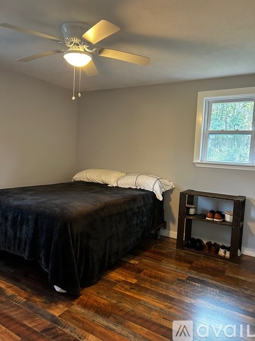 A bedroom with a bed, a nightstand, and a ceiling fan.