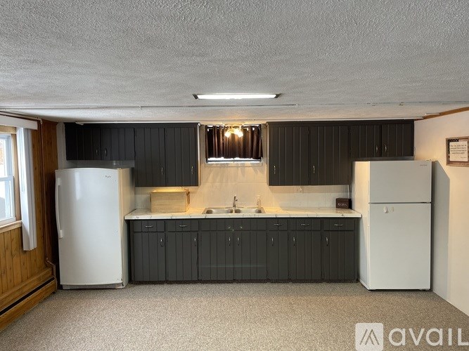 A kitchen with black cabinets and a white refrigerator.