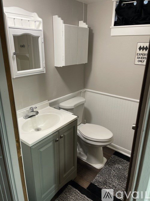 A bathroom with a toilet, sink and a mirror.