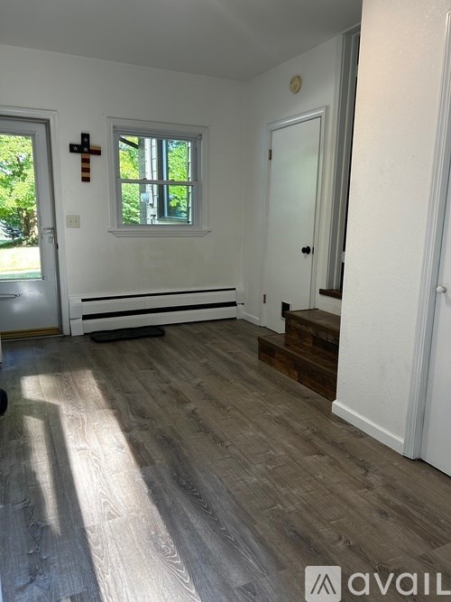 A room with wooden flooring and a white door.