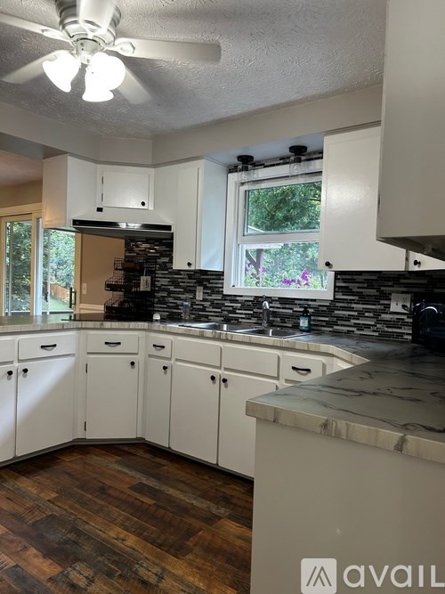A kitchen with white cabinets and a wooden floor.