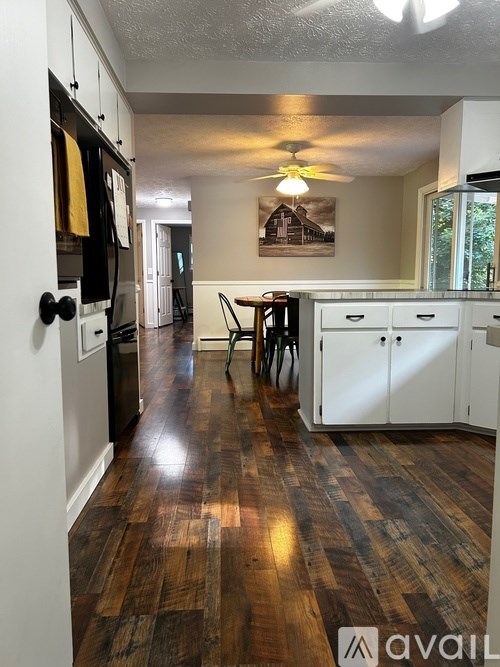 A kitchen with wooden floors and white cabinets.