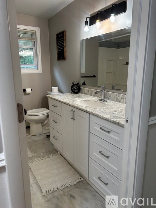 A bathroom with a marble countertop and white cabinets.