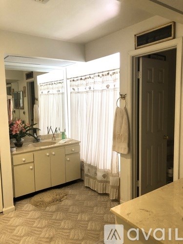 A bathroom with a sink, mirror, and towel hanging on the door.